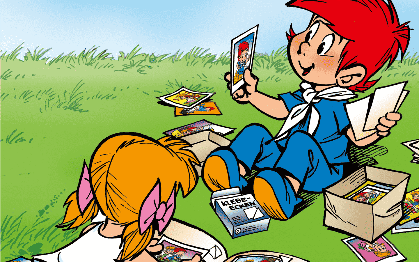 Didi und Dodo sitzen auf der Wiese und schauen Fotos an